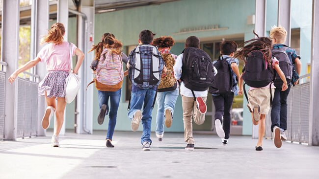 Group of elementary school kids running at school, back view