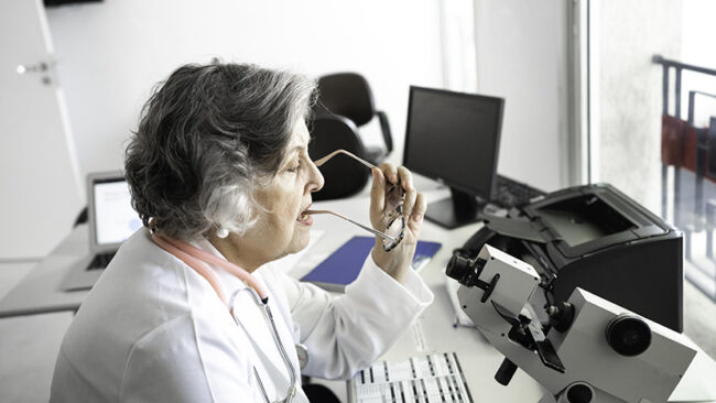 Senior female doctor analyzing eye test equipment