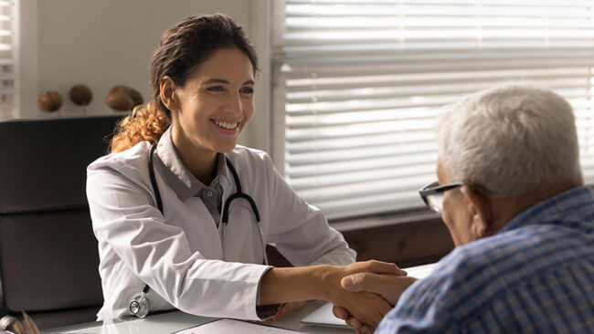 Happy physician shaking hands with grateful old man on meeting