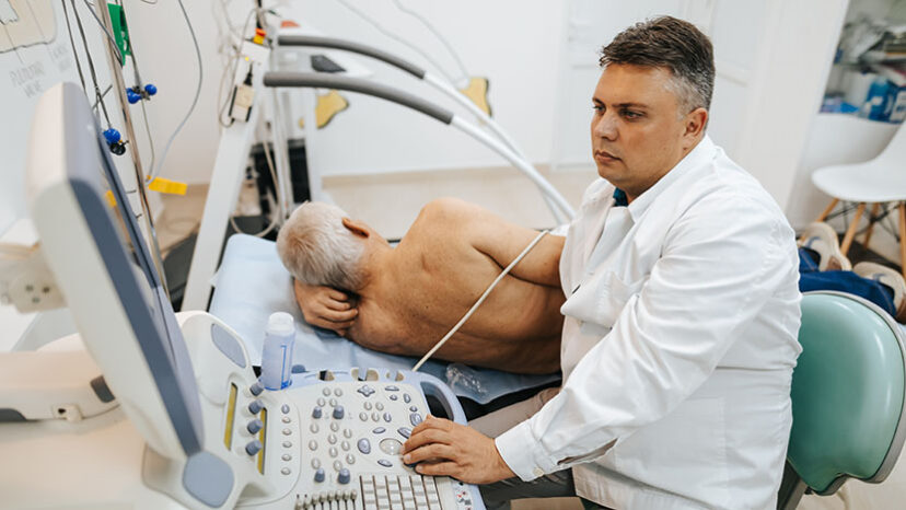 Male doctor examining a patient’s heart by using an ultrasound equipment