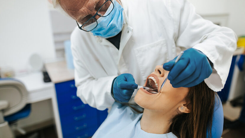 Senior dentist examining the teeth of a young woman