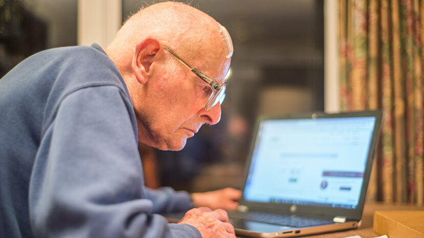 Elderly man using a laptop computer to check share portfolios ,Hampshire,England,U.K.